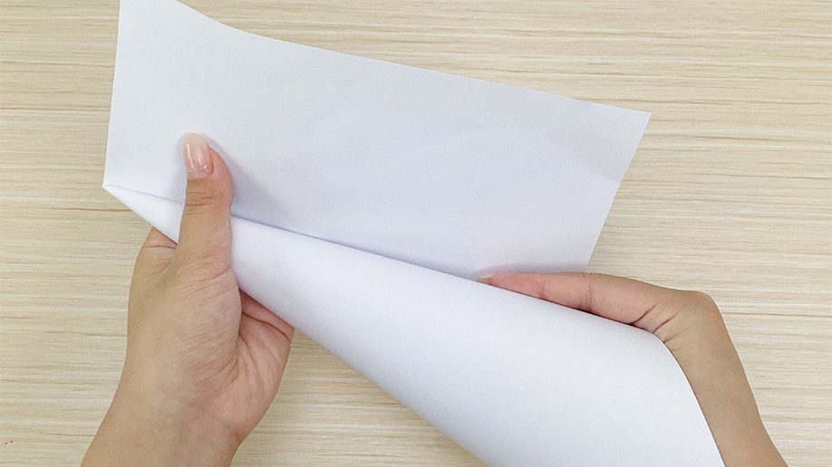 Shaping the festive base! A pair of hands carefully rolls a sheet of white paper into a cone shape, creating the foundation for a delightful Christmas tree night light. Onwards and upwards!