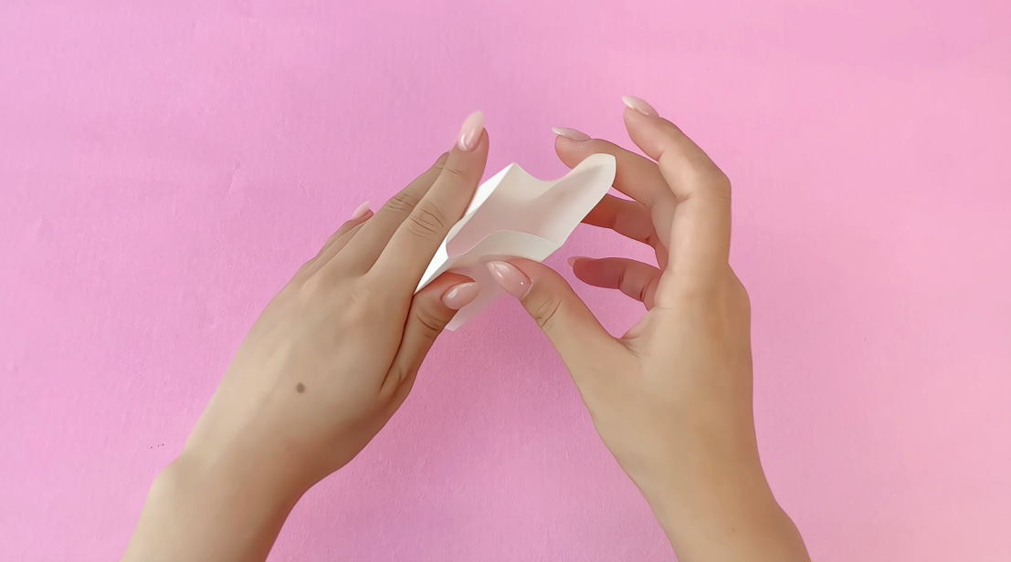 Creating a festive form! Two hands carefully shape the folded paper, creating a charming base for the dancing reindeer. It's all starting to take shape!