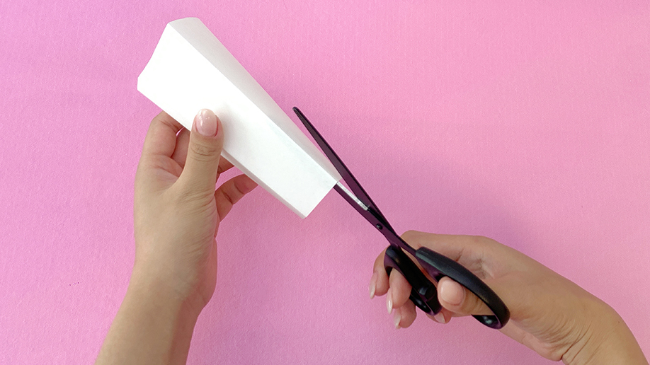 Making those cuts! A pair of hands uses scissors to carefully trim the excess paper from a folded section, creating a precise shape for the dancing reindeer. It's all shaping up nicely!