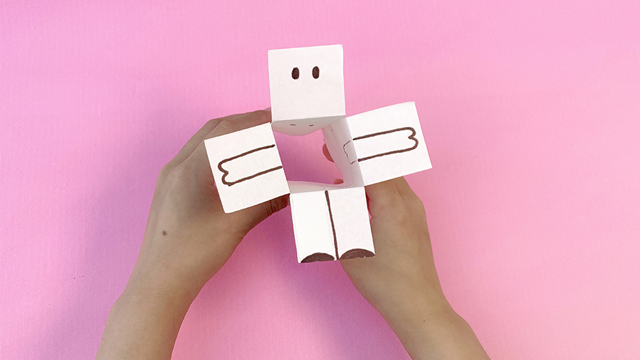 Nearly ready to dance! A pair of hands holds a partially completed paper reindeer, its simple features now clearly visible. Just a few more steps to go before these festive friends are ready to twirl!