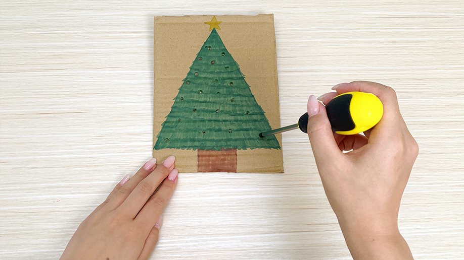 A hand carefully dips cotton buds into colorful paints arranged on a palette, preparing to add a festive touch to our Christmas tree creation. It's all rather jolly, wouldn't you say?