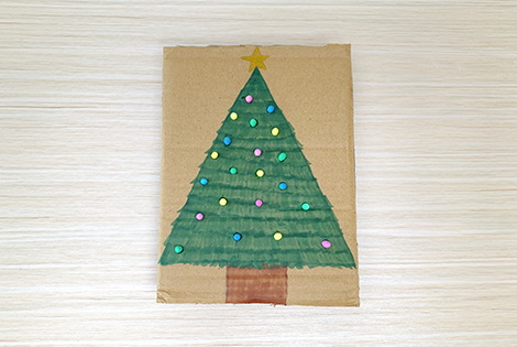 Ooh, a right festive creation! There's a charming Christmas tree, all painted and decorated, proudly displayed on a piece of cardboard. It's a lovely bit of homemade cheer, wouldn't you say?