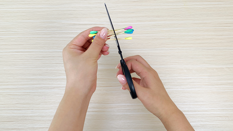 A hand carefully pushes colorful cotton buds into the holes of the painted Christmas tree, adding a festive touch. It's all looking rather jolly, wouldn't you say?