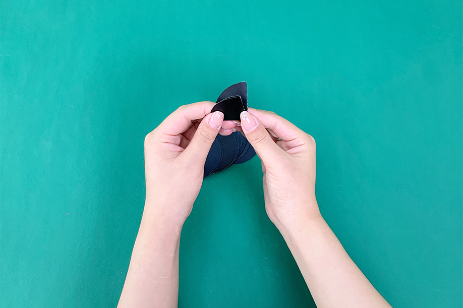 In this simple yet creative craft, a pair of hands is carefully assembling the pieces of a paper bat, perfect for Halloween decorations. The bat is being crafted from black paper, with the wings and body sections carefully folded and shaped. This type of paper craft is ideal for both children and adults, allowing them to create their own spooky decorations with just a few materials like paper, scissors, and glue. Whether used for hanging decorations or as part of a larger display, these DIY paper bats add a playful and festive touch to any Halloween celebration.