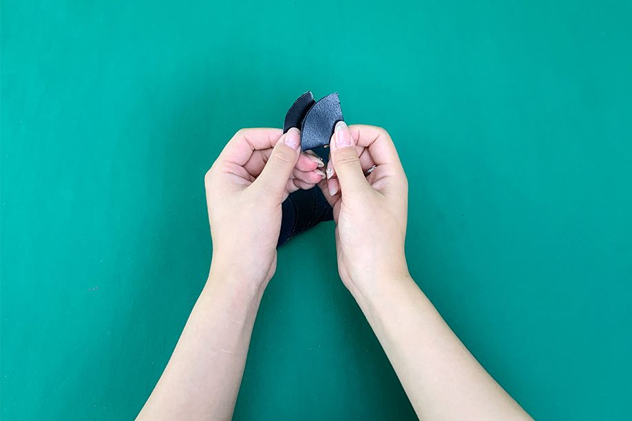 In this image, a person is delicately assembling parts of a paper bat by folding and securing black paper pieces together. The craft involves creating a 3D bat shape, perfect for Halloween decorations. This hands-on activity is easy to follow and suitable for crafters of all ages, using simple materials like black paper, glue, and adhesive strips. The completed bat can be used to adorn walls, windows, or even hung from the ceiling, adding a spooky yet charming touch to any Halloween setting.