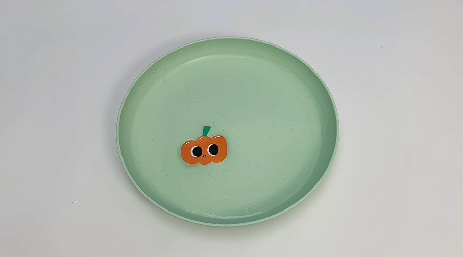 A bit of spooky charm! A sweet little pumpkin, with big, friendly eyes, sits all alone on a pale green plate. It's ready for some Halloween fun, wouldn't you say? Let's get crafting!