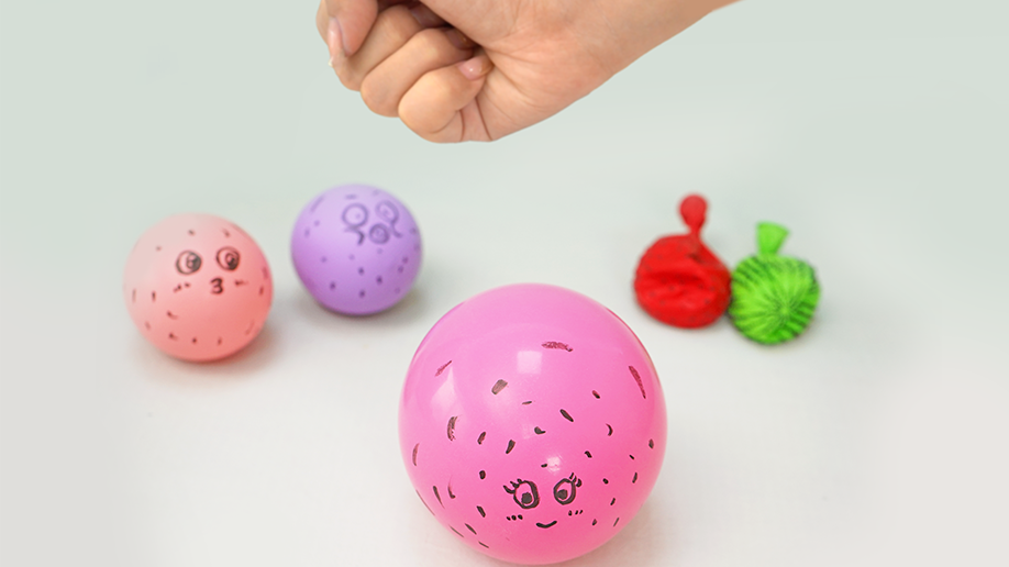 Ooh, look at that cheeky face! A hand adds the final touches to a pink balloon pufferfish, completing its cute expression. It's ready to inflate and surprise everyone with its spiky science!