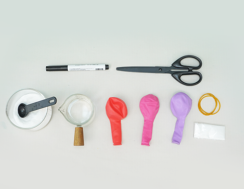 Gather your kit for some spiky science fun! You'll need a selection of colourful balloons, a black marker pen, scissors, a small jug of water, a measuring spoon of bicarbonate of soda, a rubber band, and a small plastic bag. Let's get those pufferfish inflated!