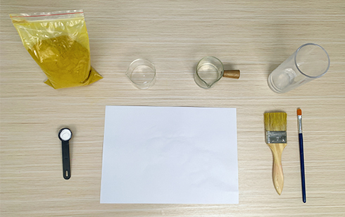 Gather your secret-making supplies, my friend! You'll need a bag of turmeric, a couple of small glasses, a larger glass, a measuring spoon, a sheet of paper, and a couple of paintbrushes – one larger, one smaller. Let's get those hidden messages ready!