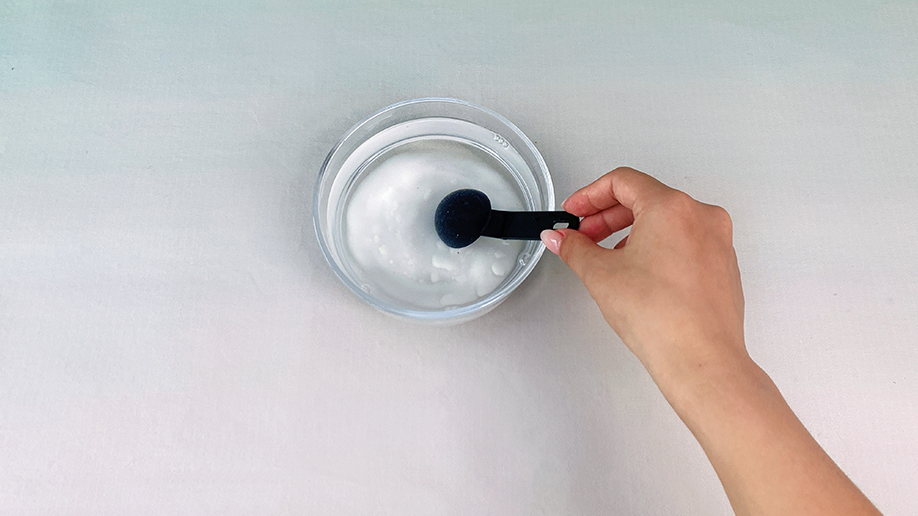  A hand is carefully adding a spoonful of borax to a bowl of water, creating the magical mixture for our growing crystals. It's all rather scientific, innit?