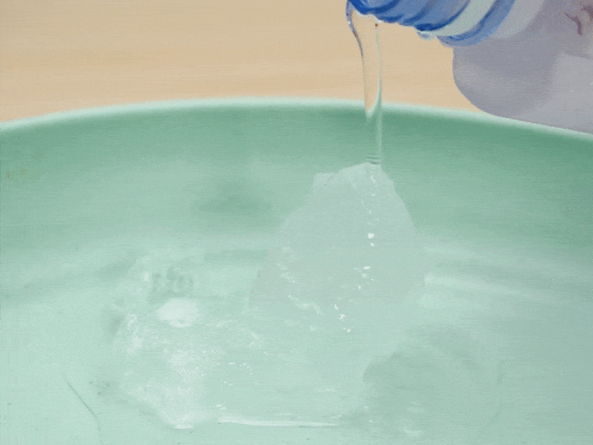 Water is poured from a plastic bottle onto a chunk of ice in a light green bowl. The ice begins to melt and reshape as the water flows over it.