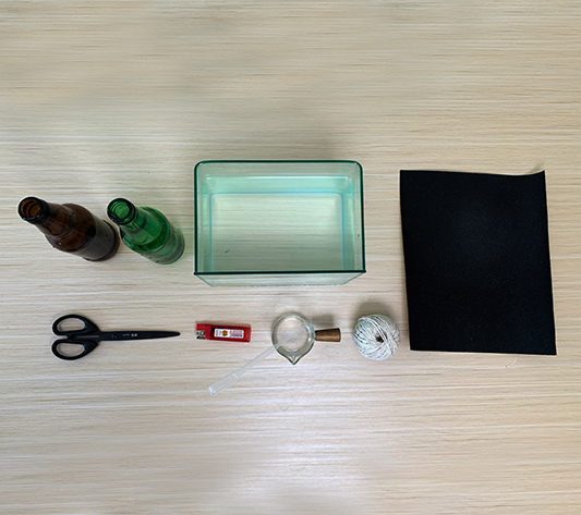 let's gather our bits and pieces! We'll need a couple of empty bottles – one brown, one green, wouldn't you know it – some string, a lighter, a small beaker, some scissors, and a bit of felt. It's all rather intriguing, innit? Let's see what we can make!