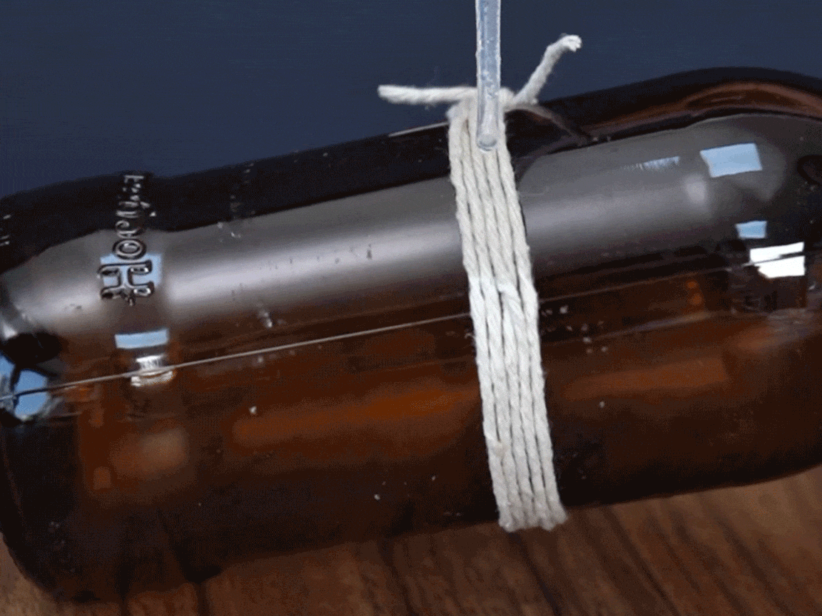  look at that! Some string is being carefully tied around a brown bottle, securing it nicely. It's all rather neat and tidy, innit? A proper bit of careful crafting!