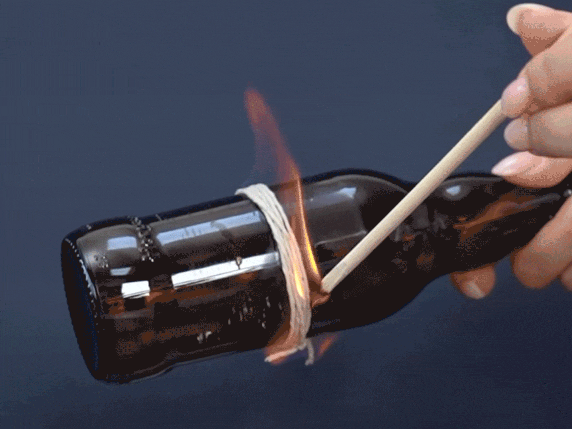 Cor blimey, be careful now! A lit match is being used to carefully burn the string wrapped around the bottle. It's all rather exciting, and a bit risky, innit? Let's hope it all goes to plan!