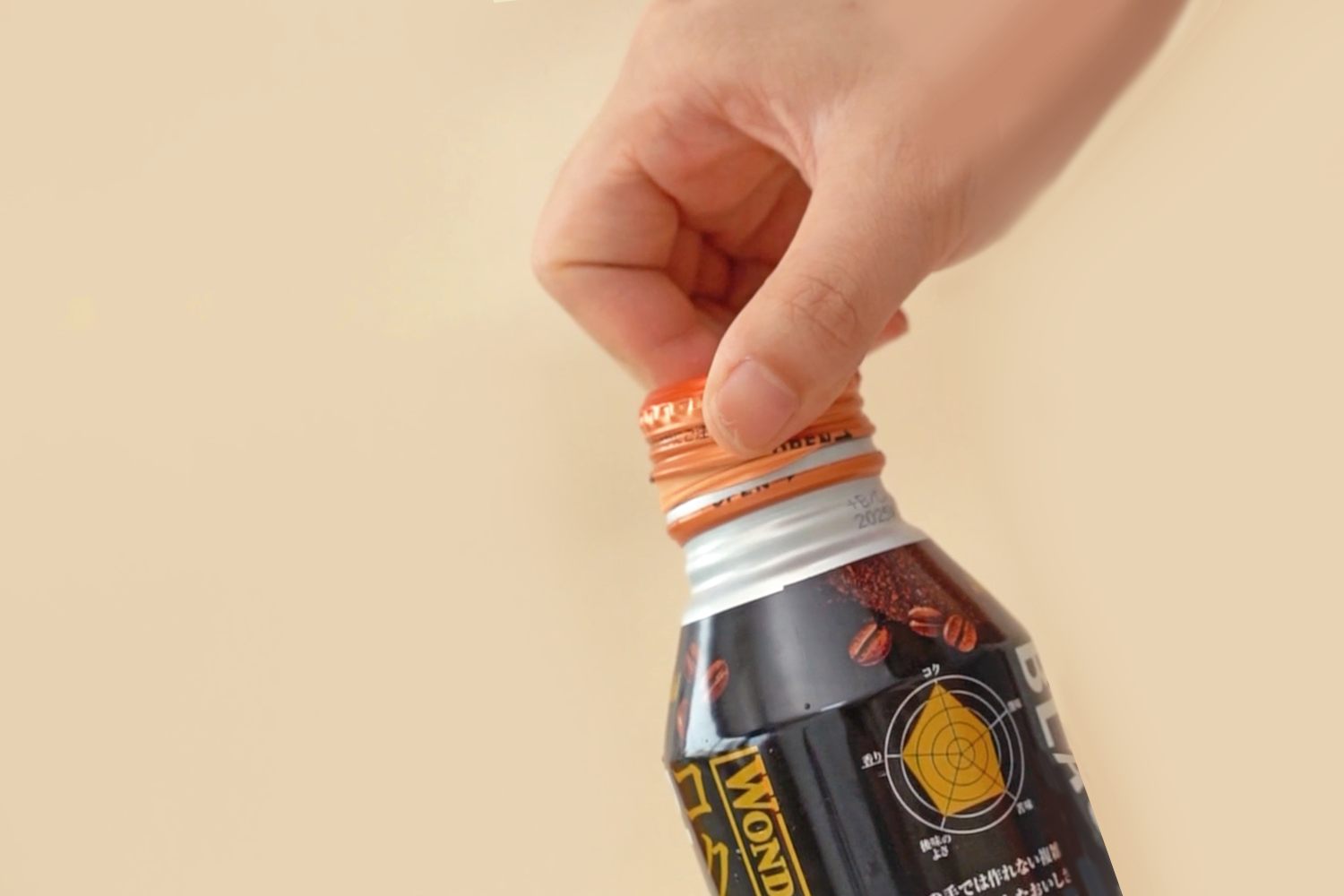 A hand is shown opening a can of Wonda coffee against a pale beige background.