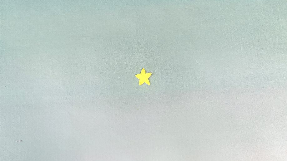 A small, yellow paper star sits centrally on a plain, textured, pale blue-grey background.