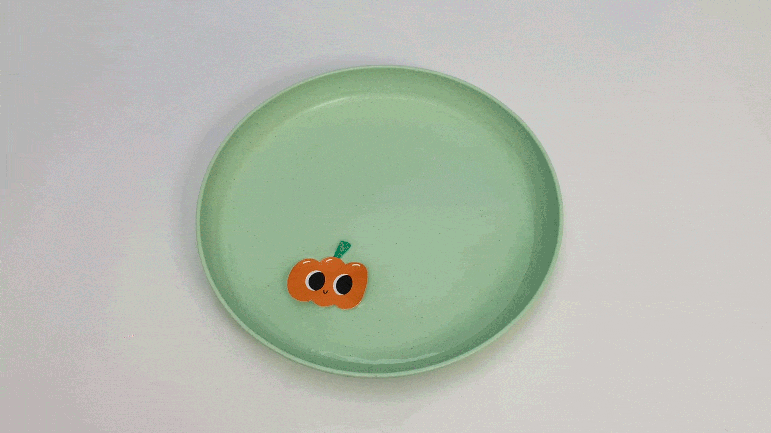 A bit of spooky charm! A sweet little pumpkin, with big, friendly eyes, sits all alone on a pale green plate. It's ready for some Halloween fun, wouldn't you say? Let's get crafting!