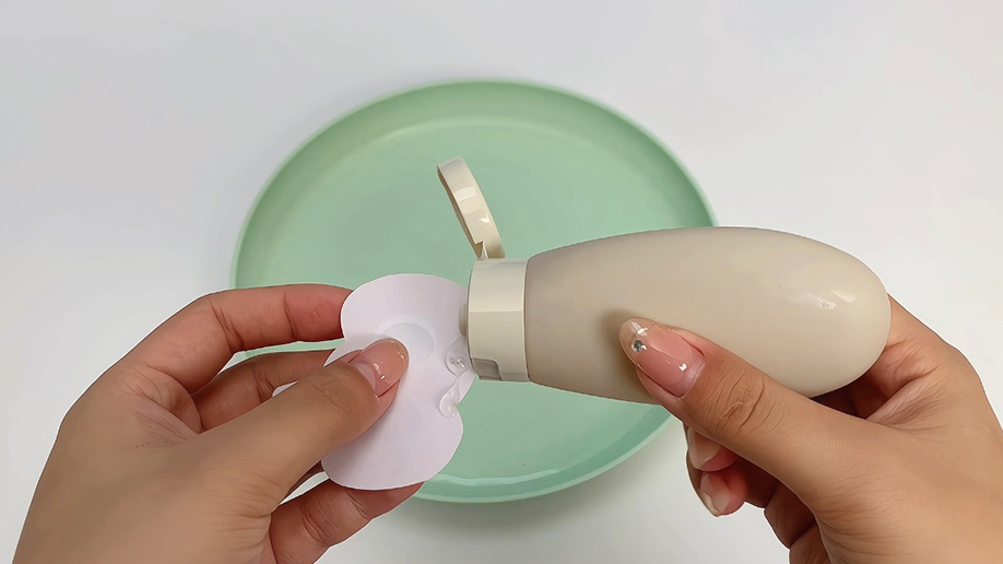 Adding the finishing touch! A hand carefully applies a clear adhesive to a paper shape, preparing it to be attached to the pale green plate. It's all coming together splendidly!