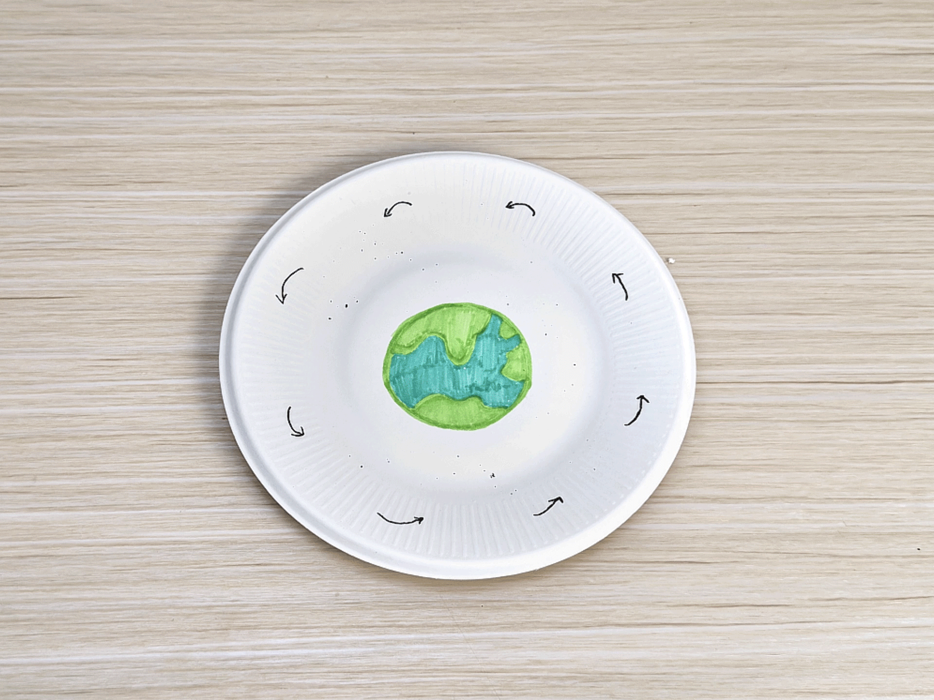A paper plate displays a simple model of the moon phases. A drawing of Earth is in the center, and Oreo cookies, with the cream filling modified to represent the different phases, are placed around it. Arrows indicate the direction of the moon's orbit. This visual aid helps explain the lunar cycle.