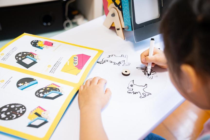 A child is engrossed in colouring pre-drawn animal shapes on a white surface, using a white marker pen, with an instruction booklet and what appears to be a shadow puppet theatre visible nearby.