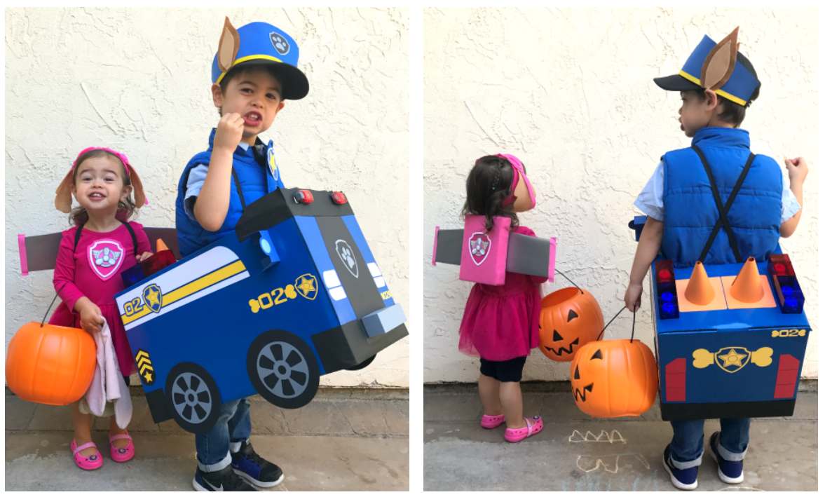 This image shows two children dressed in Paw Patrol costumes for Halloween. It's a two-part image, showing front and back views. In both, a boy wears a blue Chase police pup costume, complete with a hat with ears and a cardboard police cruiser attached to his back. He carries orange pumpkin trick-or-treat buckets. Beside him, a smaller girl wears a pink Skye costume with attached wings and carries a single orange pumpkin bucket. They stand against a light-colored wall. The right-hand image shows the back of the costumes, revealing details like the police cruiser's taillights and Skye's wings. Some chalk markings are visible on the ground in the right-hand image.