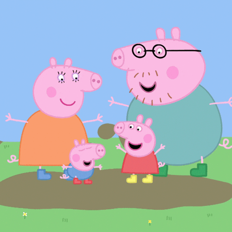 The cartoon pig family from Peppa Pig stands together in a grassy area with a muddy puddle. Mummy Pig, in an orange dress, stands on the left. Daddy Pig, wearing glasses and a teal shirt, is on the right with his arms outstretched. Peppa Pig, in a red dress, stands between her parents near the puddle, and George Pig, in blue overalls, is slightly in front of Mummy Pig. They all appear cheerful. The background is a simple light blue sky with a few small flowers scattered in the grass.