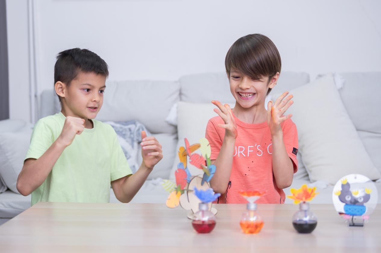 Two young boys are sitting at a table, engrossed in a craft project. The boy on the left is concentrating intently on his work, while the boy on the right is looking at his instructions. The scene is peaceful and heartwarming, capturing the joy of learning and the beauty of childhood.